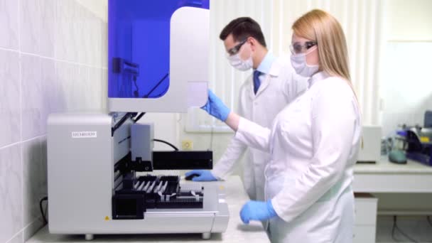 En grupp forskare bedriver forskning i ett vetenskapligt laboratorium med hjälp av avancerad teknik. — Stockvideo