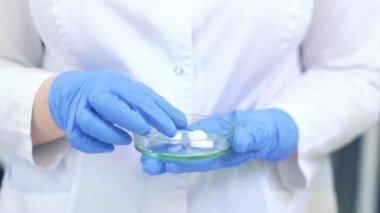 Petri kabını haplarla tutan teknisyen. Bilim adamları modern bir bilim laboratuvarında yeni ilaçlar ve aşılar üretiyorlar.