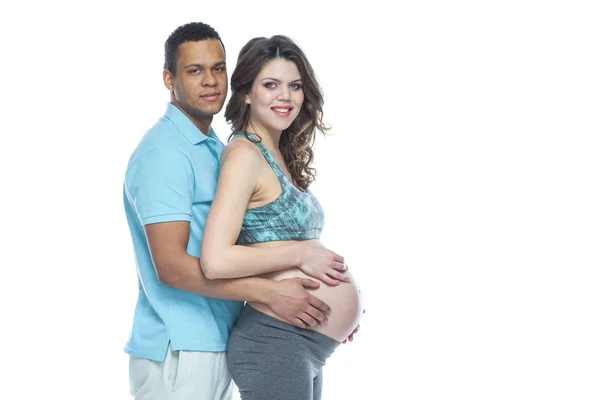 Hezký Afroameričan a jeho krásná těhotná žena se objímají a usmívají. Izolované bílé pozadí. — Stock fotografie