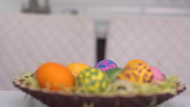 Boldog húsvétot! Egy nyúl fülű kislány bukkan fel a húsvéti tojások mögül. Boldog családi gyerekek készülnek húsvétkor. Aranyos kislány visel nyuszifül húsvét napján — Stock videók