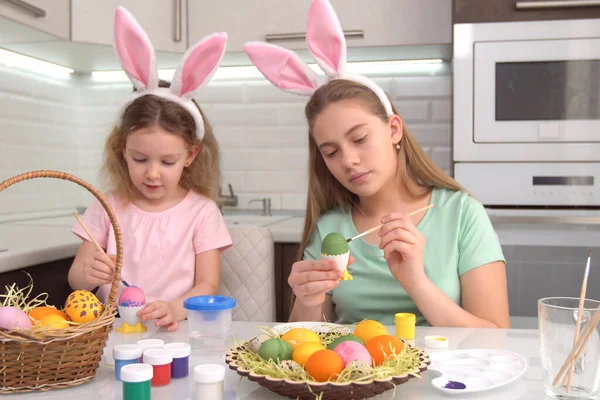 Gelukkig Pasen. Twee zussen die paaseieren schilderen. Gelukkige familie kinderen bereiden zich voor op Pasen. schattig klein kind meisje dragen bunny oren op Pasen dag. — Stockfoto