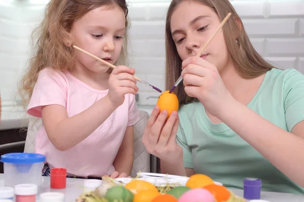 Happy easter. Two sisters painting Easter eggs. Happy family children preparing for Easter. Cute little child girl wearing bunny ears on Easter day.