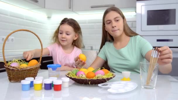 Feliz Pascua. Dos hermanas pintando huevos de Pascua. Felices hijos de familia preparándose para Pascua. Linda niña pequeña con orejas de conejo en el día de Pascua. — Vídeos de Stock