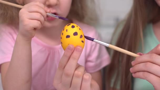 Feliz Pascua. Dos hermanas pintando huevos de Pascua. Felices hijos de familia preparándose para Pascua. Linda niña pequeña con orejas de conejo en el día de Pascua. — Vídeo de stock