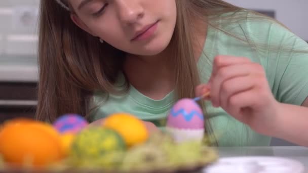 ハッピー・イースターイースターエッグを描く女の子。イースターの準備をしている幸せな家庭の子供たち。かわいい女の子を身に着けているウサギの耳でイースター日閉じるアップ — ストック動画