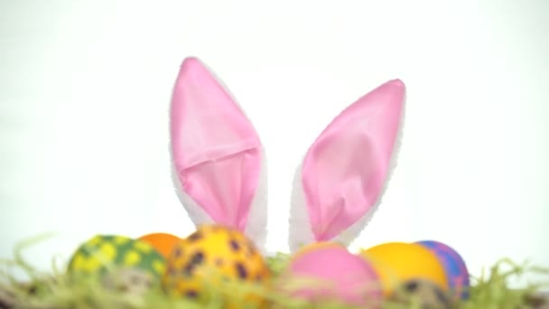 Boldog Húsvétot! Egy nyúlfülű ember néz ki a húsvéti tojások mögül. — Stock videók