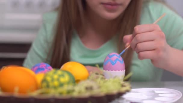 Veselé Velikonoce. Dívka maluje velikonoční vajíčka. Šťastné rodinné děti se připravují na Velikonoce. Roztomilé malé dítě dívka nosí králičí uši o velikonočním dni zblízka — Stock video