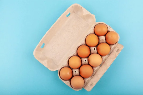 Eieren Kippeneieren. Bovenaanzicht van een open grijze doos met bruine eieren geïsoleerd op een blauwe achtergrond. Het concept van een gezonde levensstijl, het krijgen van pure eiwitten. Goed ontbijt. Dissati-eieren. — Stockfoto