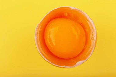 Yumurtalı tavuk yumurtası. Kahverengi yumurtanın üst görüntüsü yarı kırık, sarı yuvarlak sarısı. Sağlıklı yaşam tarzı kavramı, saf protein almak. Düzgün bir kahvaltı. Paskalya için hazırlanıyorum. Sarı renkte izole edilmiş