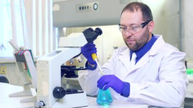 Kimyager. Bir bilim adamı bilimsel bir laboratuvarda deneyler yapar. Mikroskop kullanarak araştırma yapıyor. Evreka. - Zafer. Yeni bir keşif. Mutlu bilim adamı.