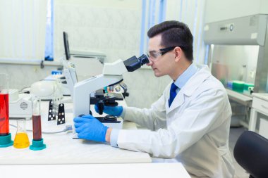 Bilimadamı bir tıp laboratuarında mikroskop altında bilimsel araştırmalar yapıyor..