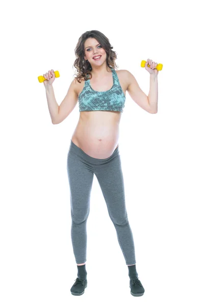 Mujer embarazada entrenando con pesas para mantenerse activa. Mujer embarazada practicando fitness y ejercitándose durante el embarazo Mujer embarazada delgada se dedica a la aptitud. Fondo blanco aislado . —  Fotos de Stock