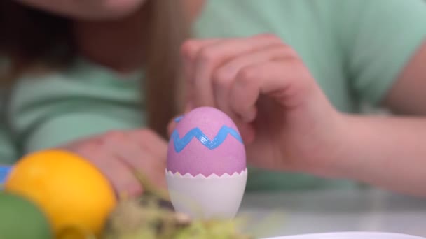 Щасливого Великодня. Дівчина малює великодні яйця. Щасливі сімейні діти готуються до Великодня. Симпатична маленька дівчинка у вухах кролика на Великдень Крупним планом — стокове відео