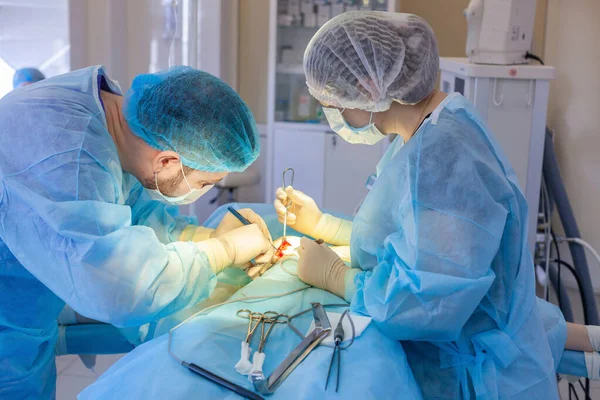 Kórházba. A sebész a műtőben dolgozik. A sebész elkezdi a mellnagyobbítást.. — Stock Fotó