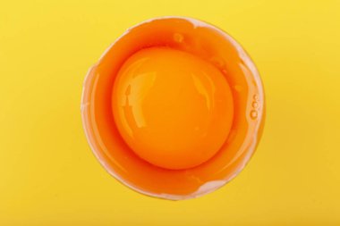 Yumurtalı tavuk yumurtası. Kahverengi yumurtanın üst görüntüsü yarı kırık, sarı yuvarlak sarısı. Sağlıklı yaşam tarzı kavramı, saf protein almak. Düzgün bir kahvaltı. Paskalya için hazırlanıyorum. Sarı renkte izole edilmiş