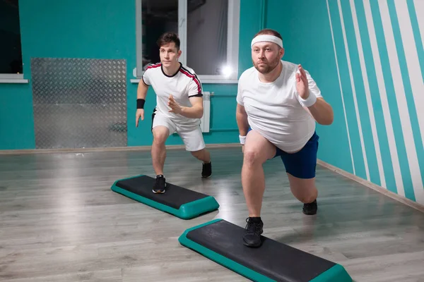 在集体健身课上，胖男人非常刻苦地在台阶上做踏步练习。体重超标 — 图库照片
