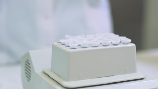 Εργαστηριακός υπάλληλος βάζει δείγματα σε ένα δίσκο κάνοντας ανάλυση για ιούς ανοσίας σε ένα ιατρικό εργαστήριο — Αρχείο Βίντεο