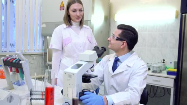 Een groep wetenschappers doet onderzoek in een wetenschappelijk laboratorium met behulp van geavanceerde technologie. Wetenschappers lachen, grapten in de werkgroep. Vreugde. — Stockvideo