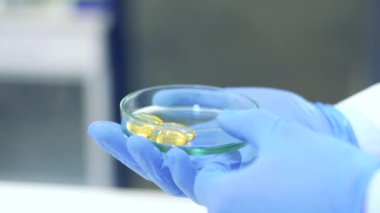 Bilim adamı bir tıp laboratuarında mikroskop ve laboratuvar ekipmanları kullanarak Omega 3 yağ asitlerinin özelliklerini ve faydalarını araştırıyor.