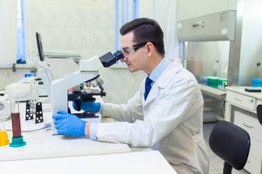 Bilimadamı bir tıp laboratuarında mikroskop altında bilimsel araştırmalar yapıyor..