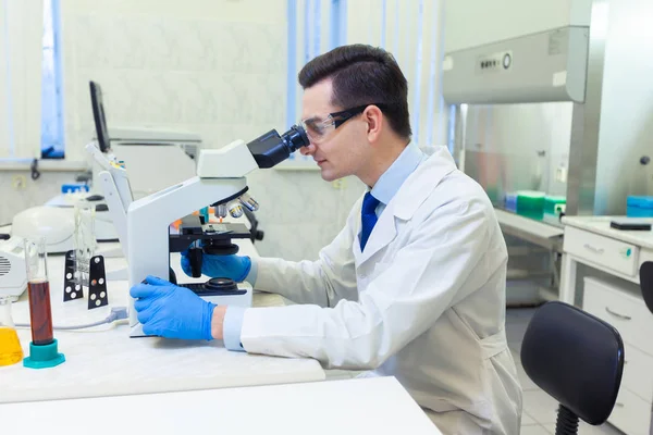 Вчений проводить наукові дослідження, дивлячись через мікроскоп в медичній лабораторії . — стокове фото