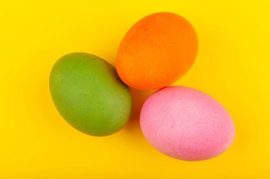 Renkli el yapımı Paskalya yumurtaları. Üç yumurtanın üst görüntüsü. Sarı arka planda izole edilmiş. Paskalya için hazırlanılıyor.