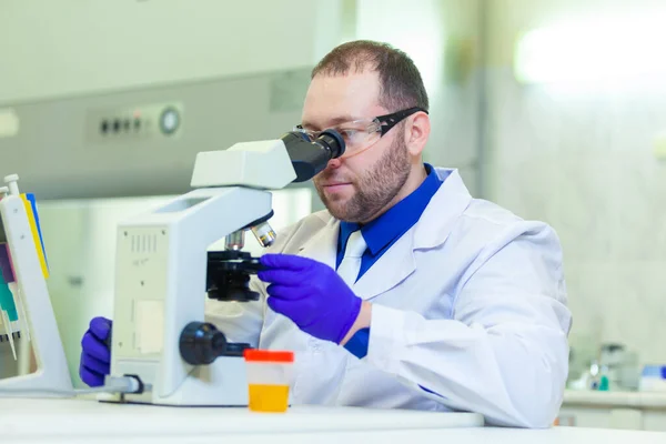 Laboratoriearbetare som utför urinanalys med hjälp av mikroskop och laboratorieutrustning i ett medicinskt laboratorium — Stockfoto