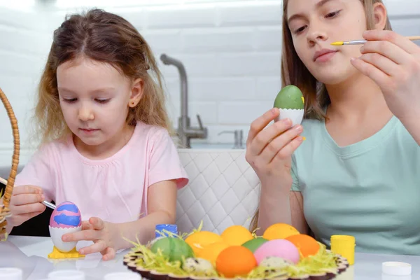 Gelukkig Pasen. Twee zussen die paaseieren schilderen. Gelukkige familie kinderen bereiden zich voor op Pasen. schattig klein kind meisje dragen bunny oren op Pasen dag. — Stockfoto