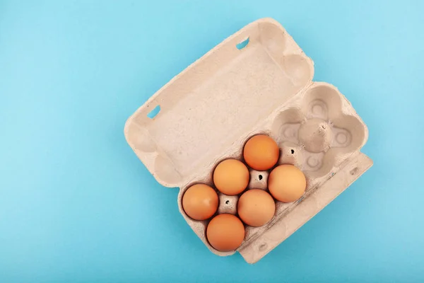 Huevos de pollo. Vista superior de una caja gris abierta con huevos marrones Aislados sobre un fondo azul. El concepto de un estilo de vida saludable, obtener proteínas puras. Desayuno apropiado. Seis huevos . — Foto de Stock