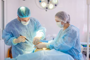 Hastanedeyiz. Cerrah ameliyathanede ameliyat yapar. Hastaya tıbbi yardım sağlanıyor..