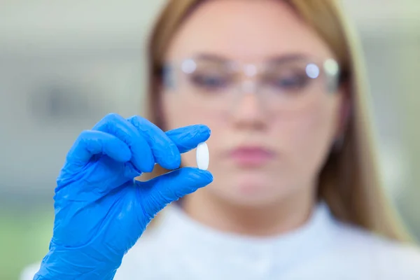 Tekniker som håller ett piller. Forskare skapar nya läkemedel och vacciner i ett modernt vetenskapligt laboratorium. — Stockfoto