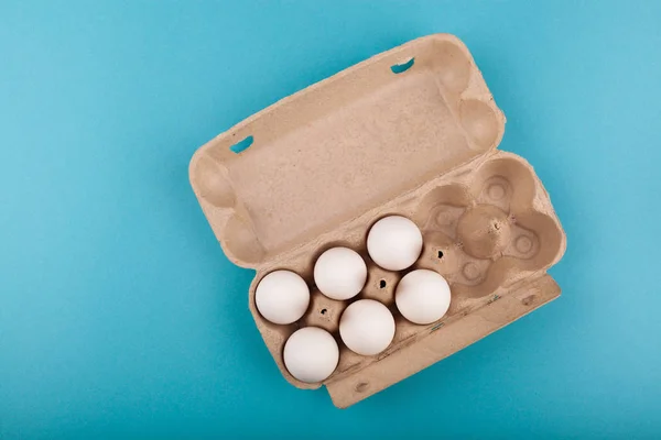 Huevos de pollo. Vista superior de una caja gris abierta con huevos blancos. Aislado sobre un fondo azul. El concepto de un estilo de vida saludable, obtener proteínas puras. Desayuno apropiado. Seis huevos . — Foto de Stock