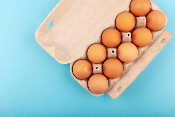 Huevos de pollo. Vista superior de una caja gris abierta con huevos marrones Aislados sobre un fondo azul. El concepto de un estilo de vida saludable, obtener proteínas puras. Desayuno apropiado. Huevos dissati . — Foto de Stock