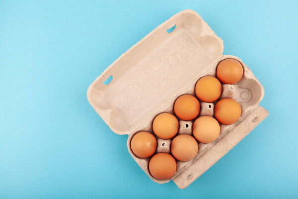 Egg Chicken eggs. Top view of an open gray box with brown eggs Isolated on a blue background. The concept of a healthy lifestyle, getting pure protein. Proper Breakfast. Nine eggs.
