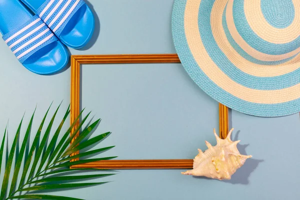 Вид сверху на полосатую синюю шляпу, флип-флопс, пальмовый лист, морковь и рамку для отпускных фотографий на бирюзово-голубом фоне. Концепция пляжного отдыха, морской тур, теплое солнечное лето. Copy-paste — стоковое фото