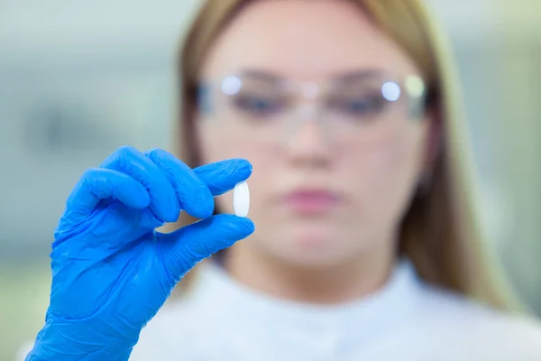 Tekniker som håller ett piller. Forskare skapar nya läkemedel och vacciner i ett modernt vetenskapligt laboratorium. — Stockfoto