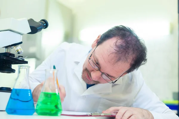 Químico loco. Un científico loco realiza experimentos en un laboratorio científico. Intención de registrar los resultados del estudio . —  Fotos de Stock