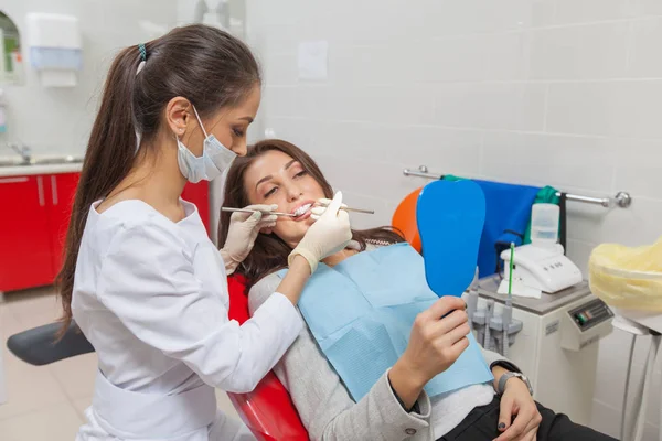 Dentist. A woman in the dentists office examines her teeth in the mirror and smiles. — Stock Photo, Image