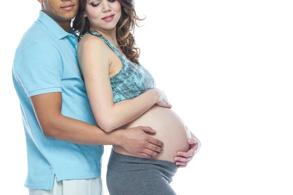 Hezký Afroameričan a jeho krásná těhotná žena se objímají a usmívají. Izolované bílé pozadí. — Stock fotografie