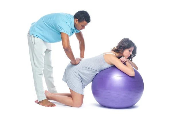 A young black man helps his white wife with birth pain with a ball. Partnered birth, partnered delivery. Isolated white background. — Stock Photo, Image