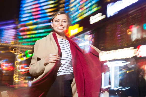 Vidám lány divatos ruházati izgatott éjszakai fények Big City, gyönyörű barna nő boldog töltenek este szabad időt a belvárosban neon megvilágítás. — Stock Fotó