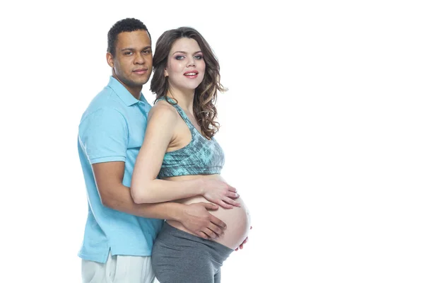 Pohledný černoch se svou krásnou těhotnou manželkou se při tom směje a usmívá se. Izolované bílé pozadí. — Stock fotografie