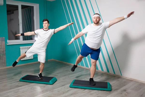 El hombre gordo es muy trabajador haciendo ejercicios en los pasos con las manos en alto durante las clases de fitness grupales. Peso excesivo — Foto de Stock