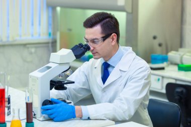 Bilimadamı bir tıp laboratuarında mikroskop altında bilimsel araştırmalar yapıyor. COVID-19. COVID Coronavirüs