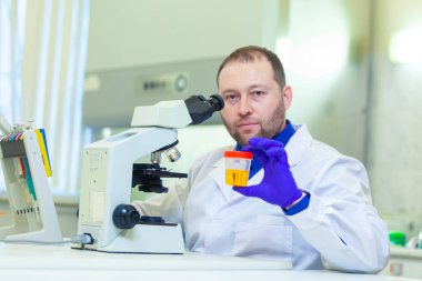 Laboratuvar çalışanı bir tıp laboratuarında mikroskop ve laboratuvar ekipmanları kullanarak idrar tahlili yapıyor.