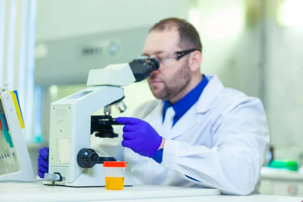 Εργαστηριακός εργαζόμενος που εκτελεί ανάλυση ούρων με μικροσκόπιο και εργαστηριακό εξοπλισμό σε ιατρικό εργαστήριο — Φωτογραφία Αρχείου