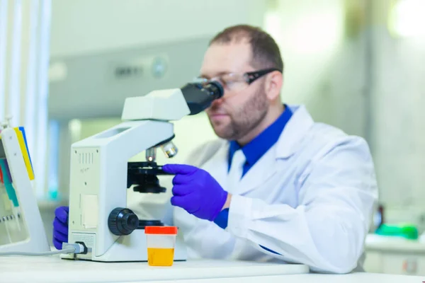 Trabajador de laboratorio que realiza análisis de orina utilizando microscopio y equipo de laboratorio en un laboratorio médico —  Fotos de Stock