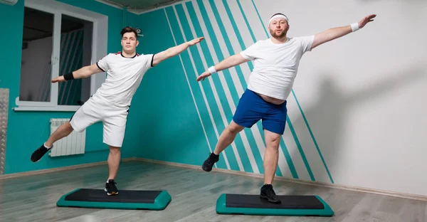 El hombre gordo es muy trabajador haciendo ejercicios en los pasos con las manos en alto durante las clases de fitness grupales. Peso excesivo — Foto de Stock