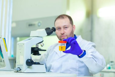 Laboratuvar çalışanı bir tıp laboratuarında mikroskop ve laboratuvar ekipmanları kullanarak idrar tahlili yapıyor.