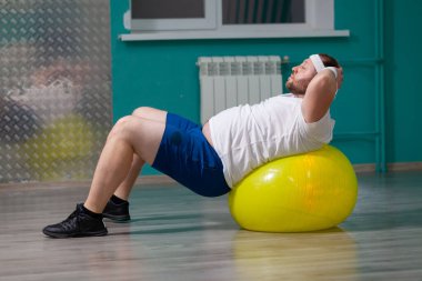 Kilolu bir adam grup fitness dersleri sırasında spor salonunda yalan söylüyor. Şişman adam kilo verme eğitiminin kötü sonucu yüzünden hayal kırıklığına uğramış görünüyor.